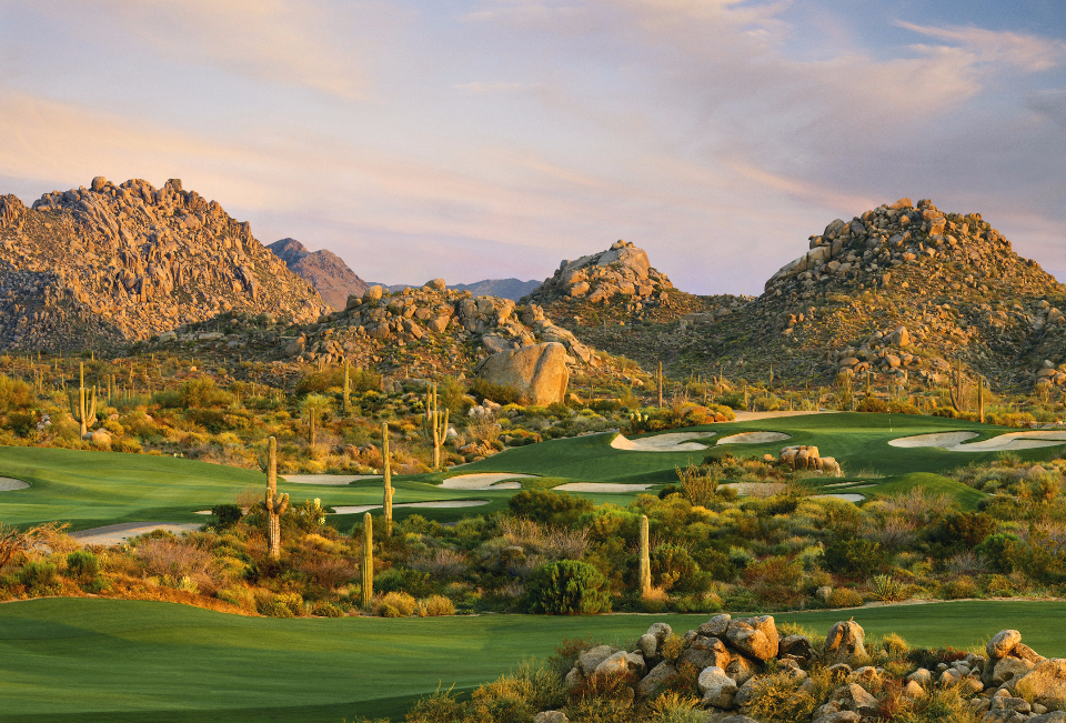 Lush desert golf course with saguaro cacti and rocky mountains at golden hour