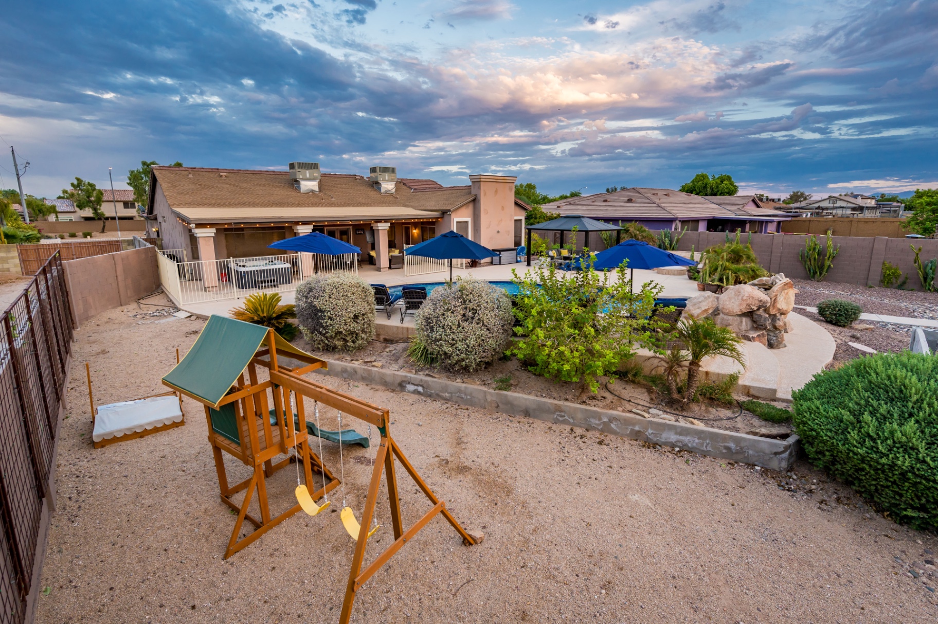 Aerial sunset view of backyard with pool, gazebos, play set and patio