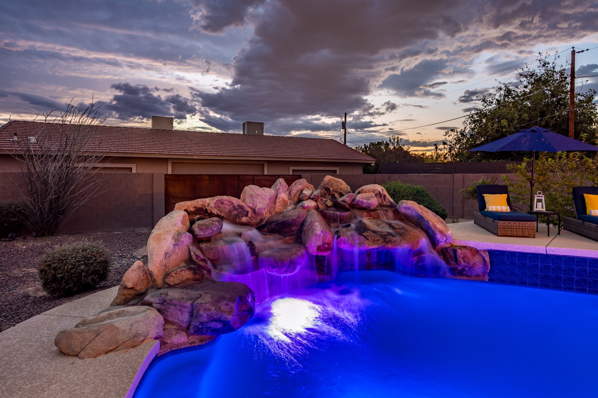 Grotto waterfall lit purple at sunset with dramatic clouds overhead