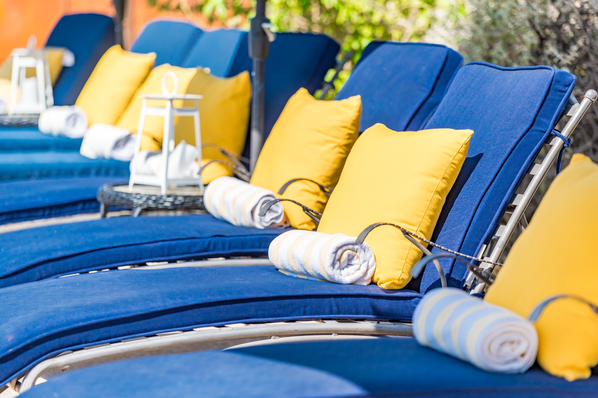 Row of blue loungers with yellow pillows and rolled striped towels