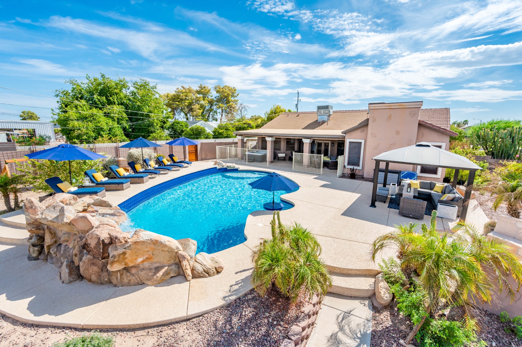 Wide backyard view with pool, loungers, gazebo and desert landscaping