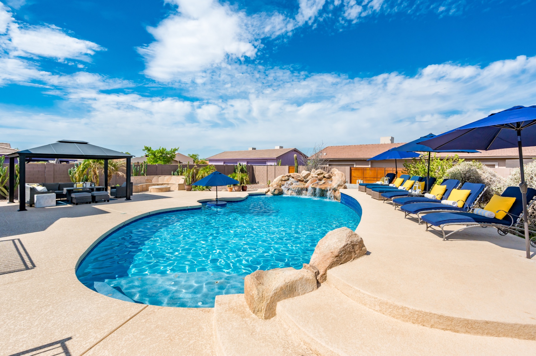 Backyard pool with grotto waterfall, loungers and shaded gazebo