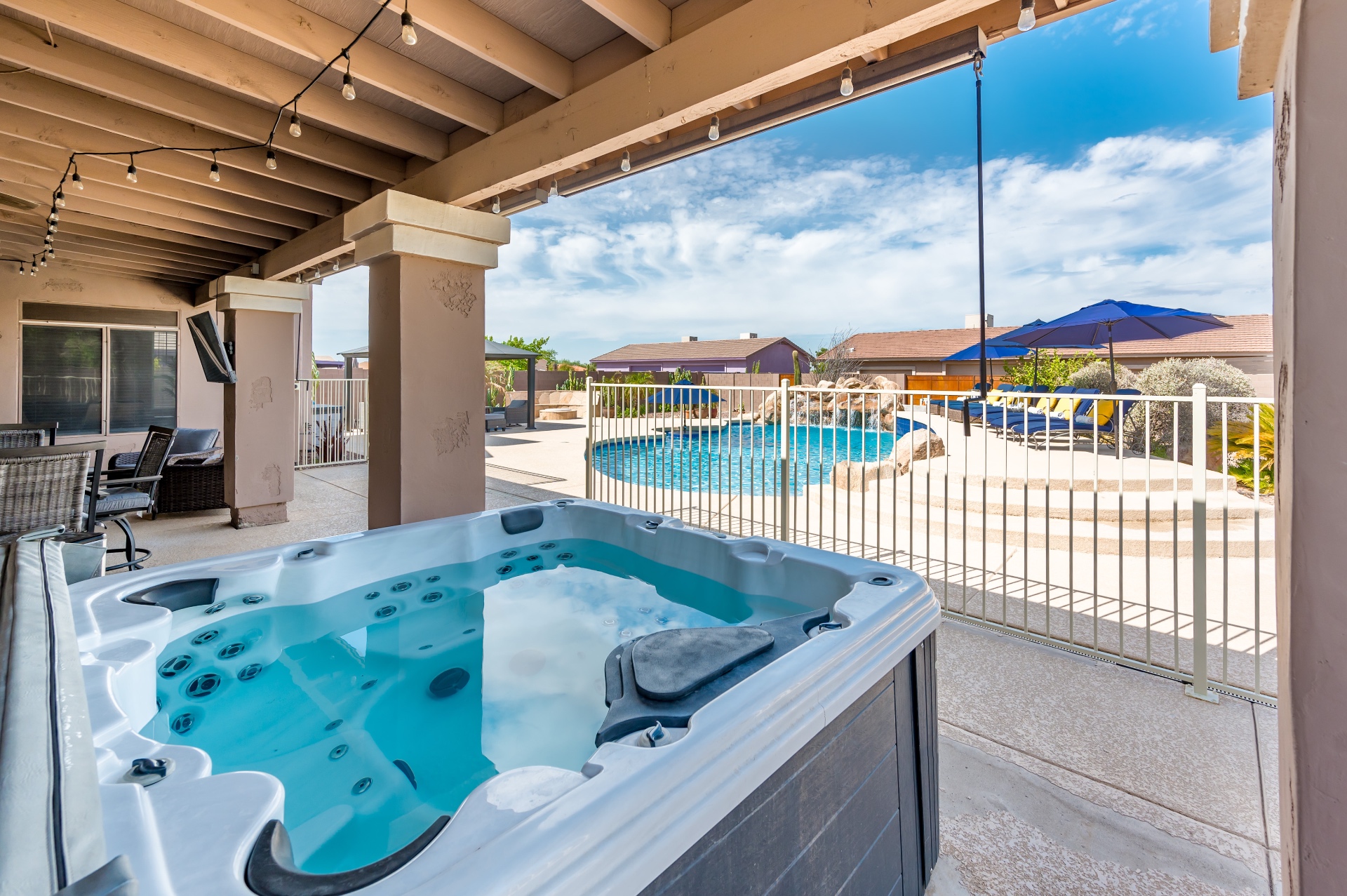 Covered patio hot tub with jets, overlooking the fenced pool area