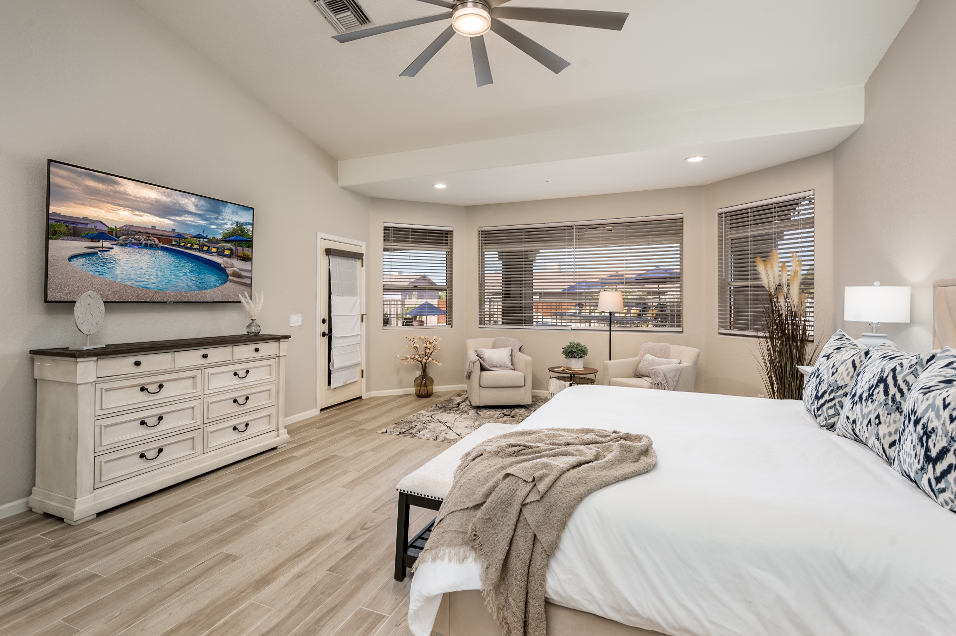 Primary bedroom with mounted TV, dresser and patio access