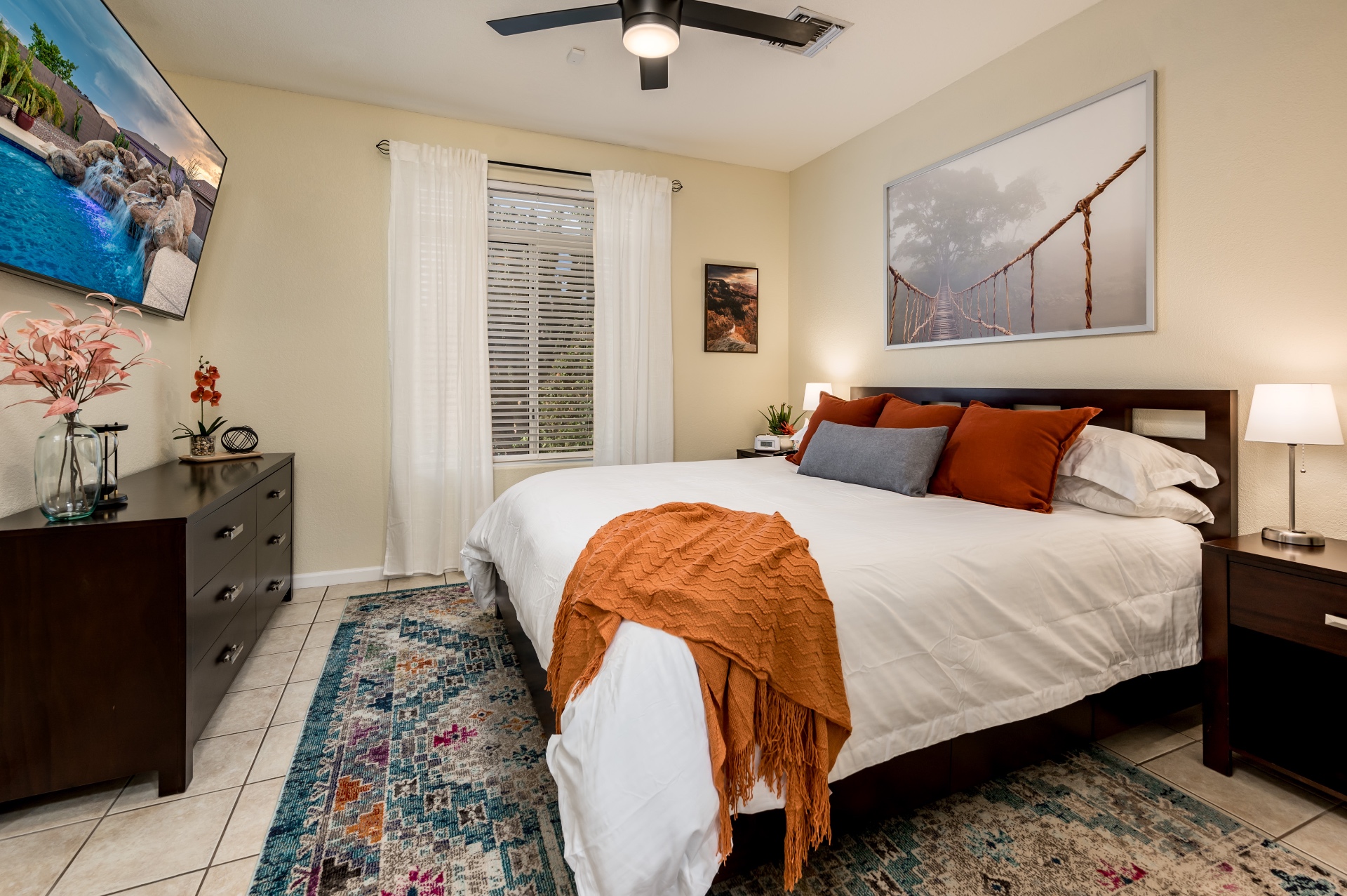 Guest bedroom with king bed, orange accents and mounted TV