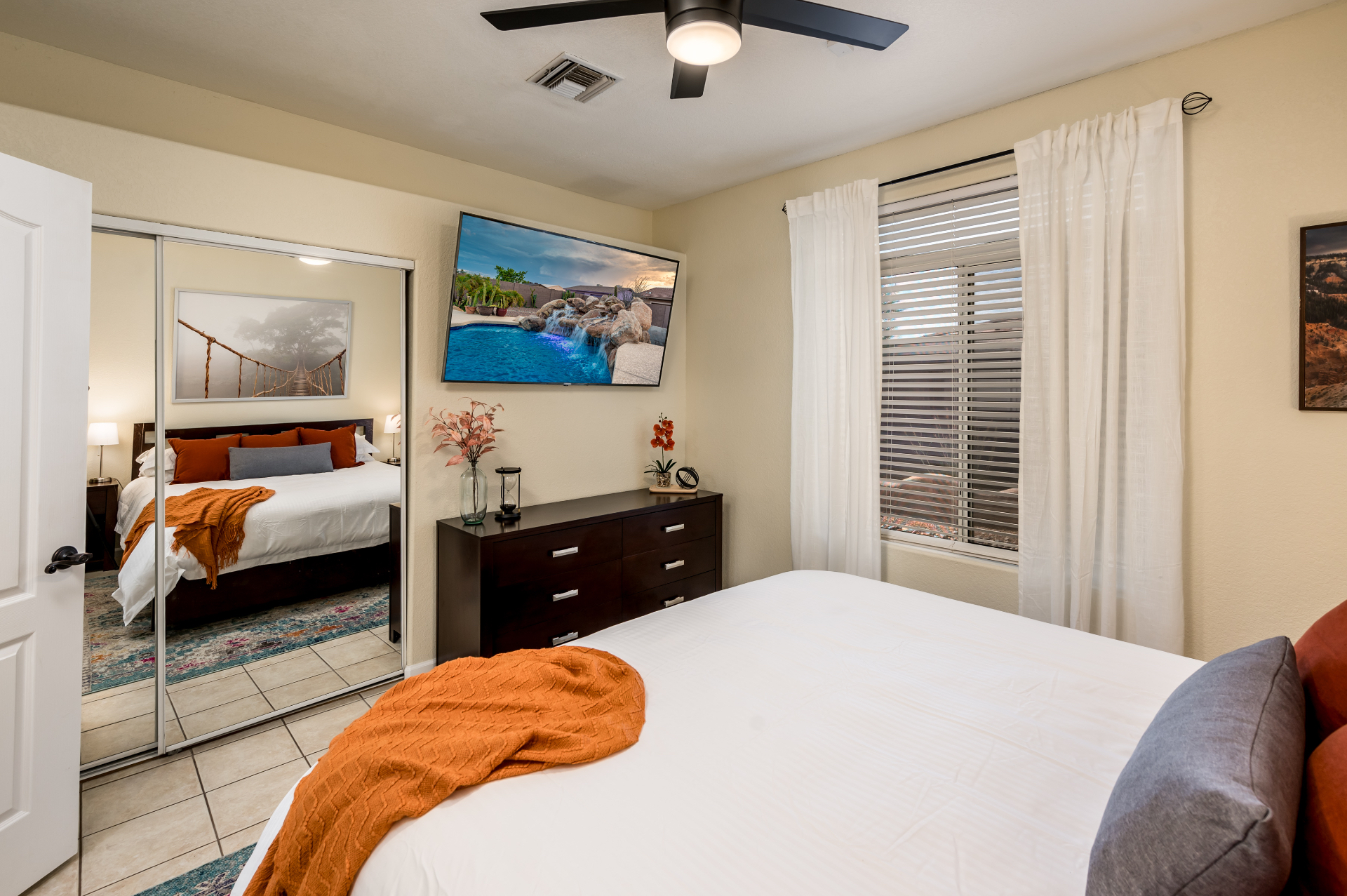 Guest bedroom showing mirrored closet, dresser and TV