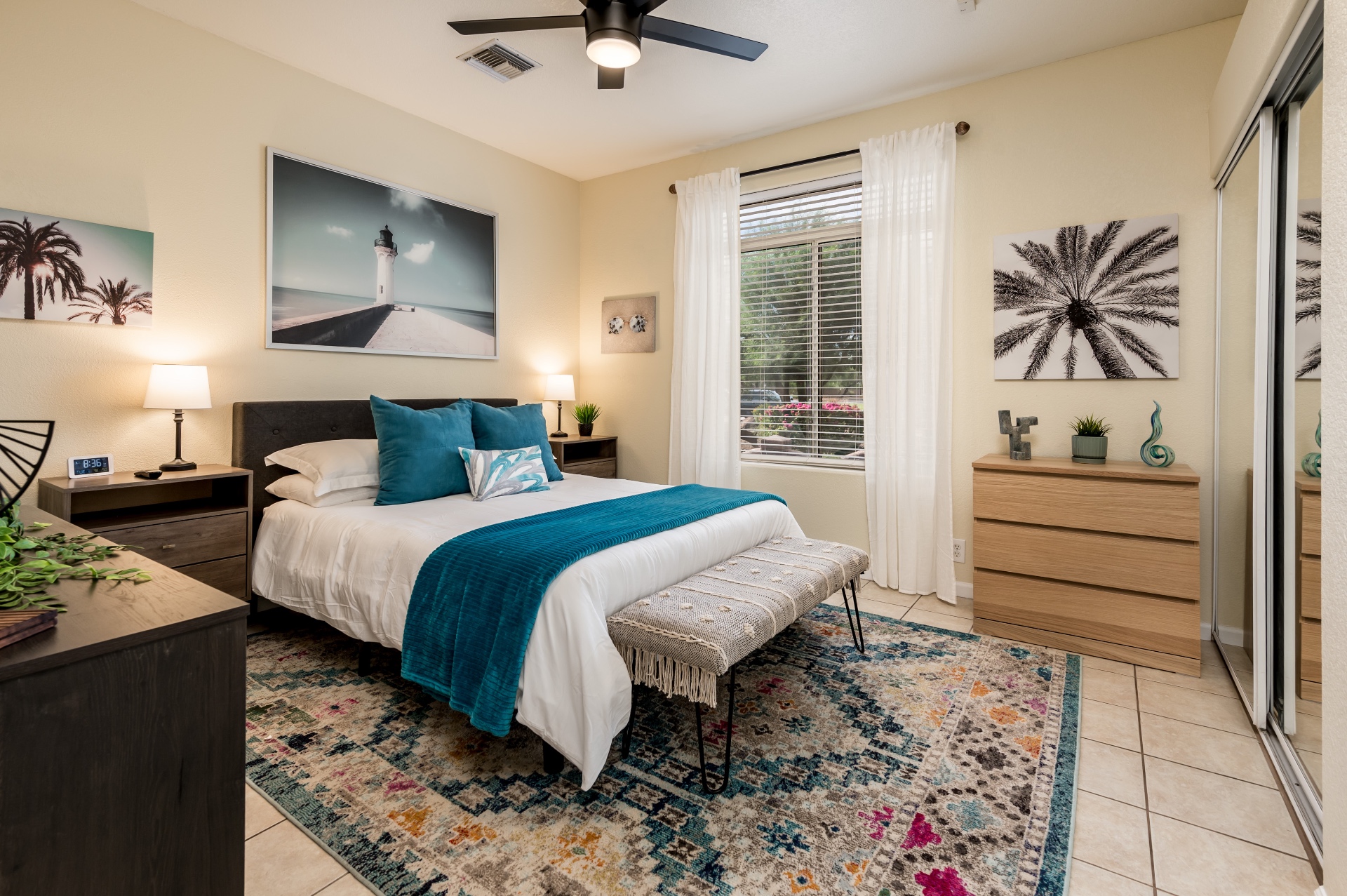 Coastal-themed bedroom with queen bed, teal accents and palm art