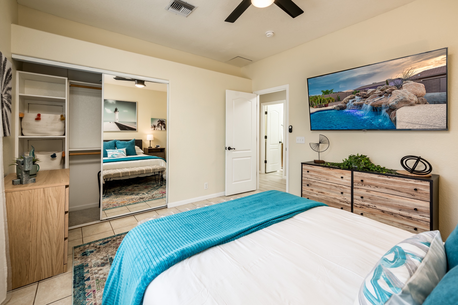 Coastal bedroom view with mirrored closet and mounted TV