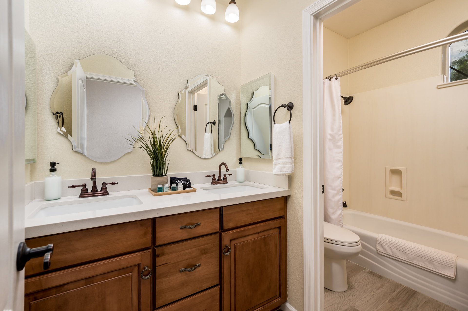 Hall bathroom with double vanity, decorative mirrors and shower-tub