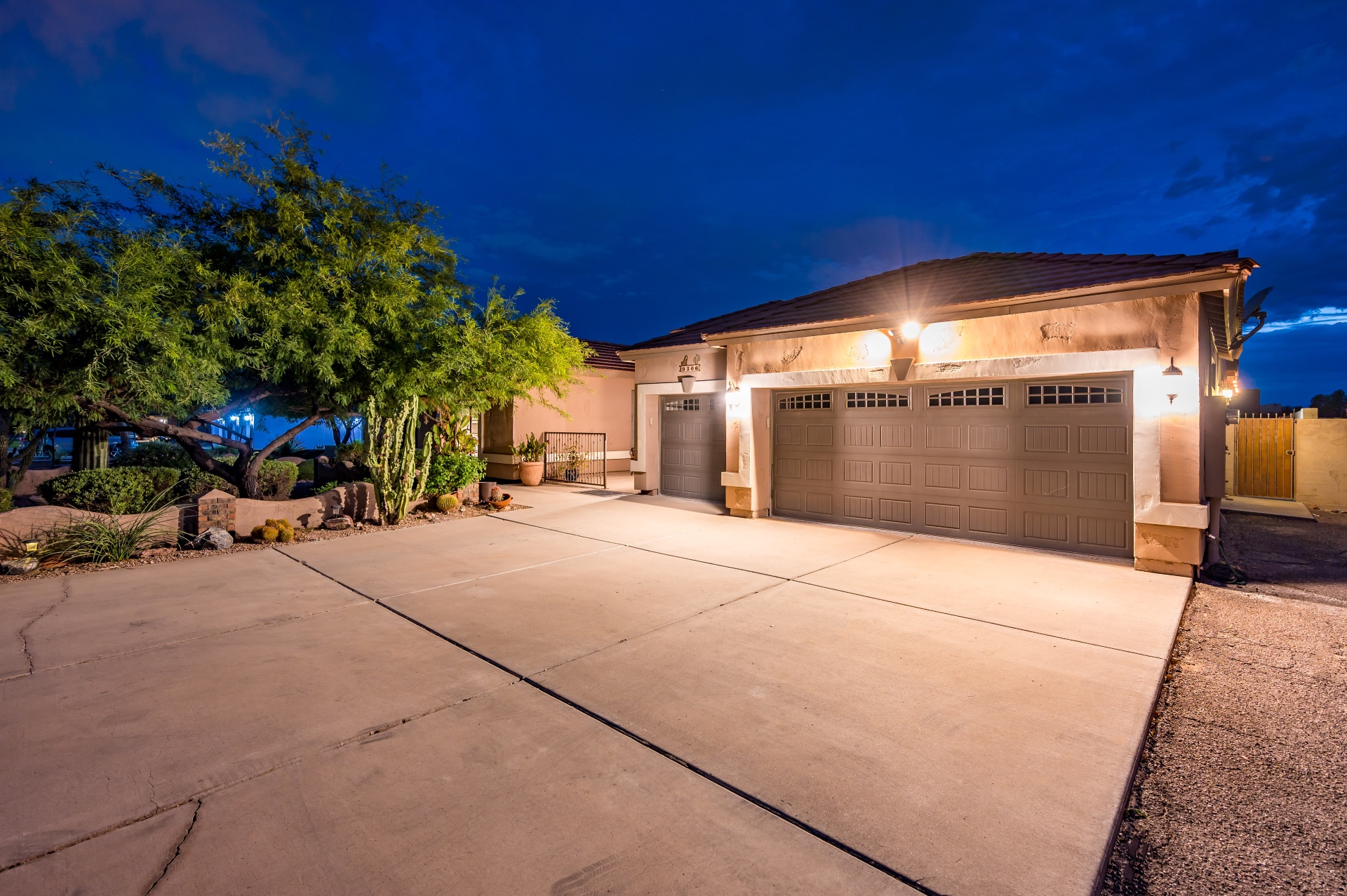 Twilight exterior with warm lights and three-car garage