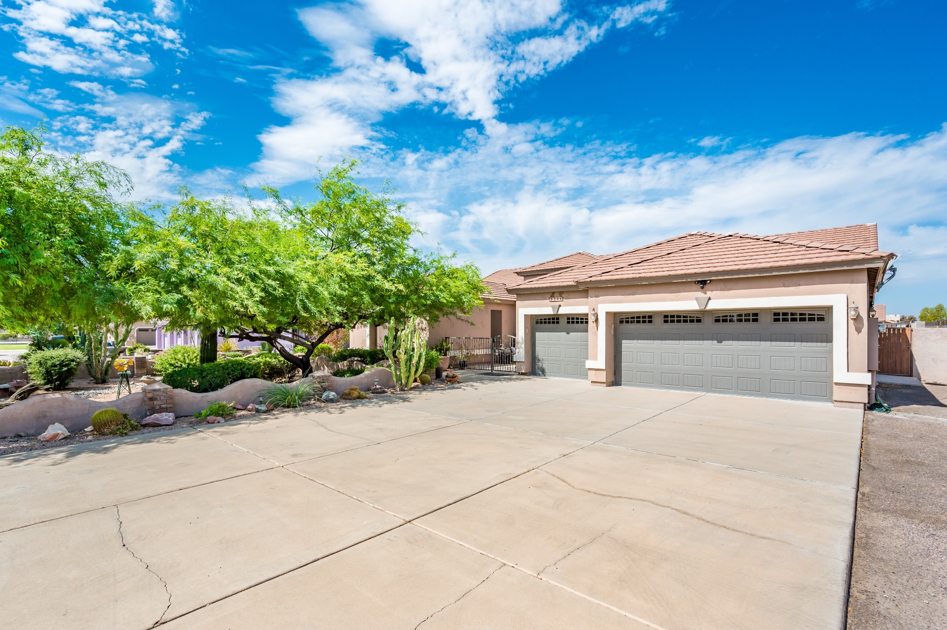 Driveway view of the three-car garage and desert landscaping