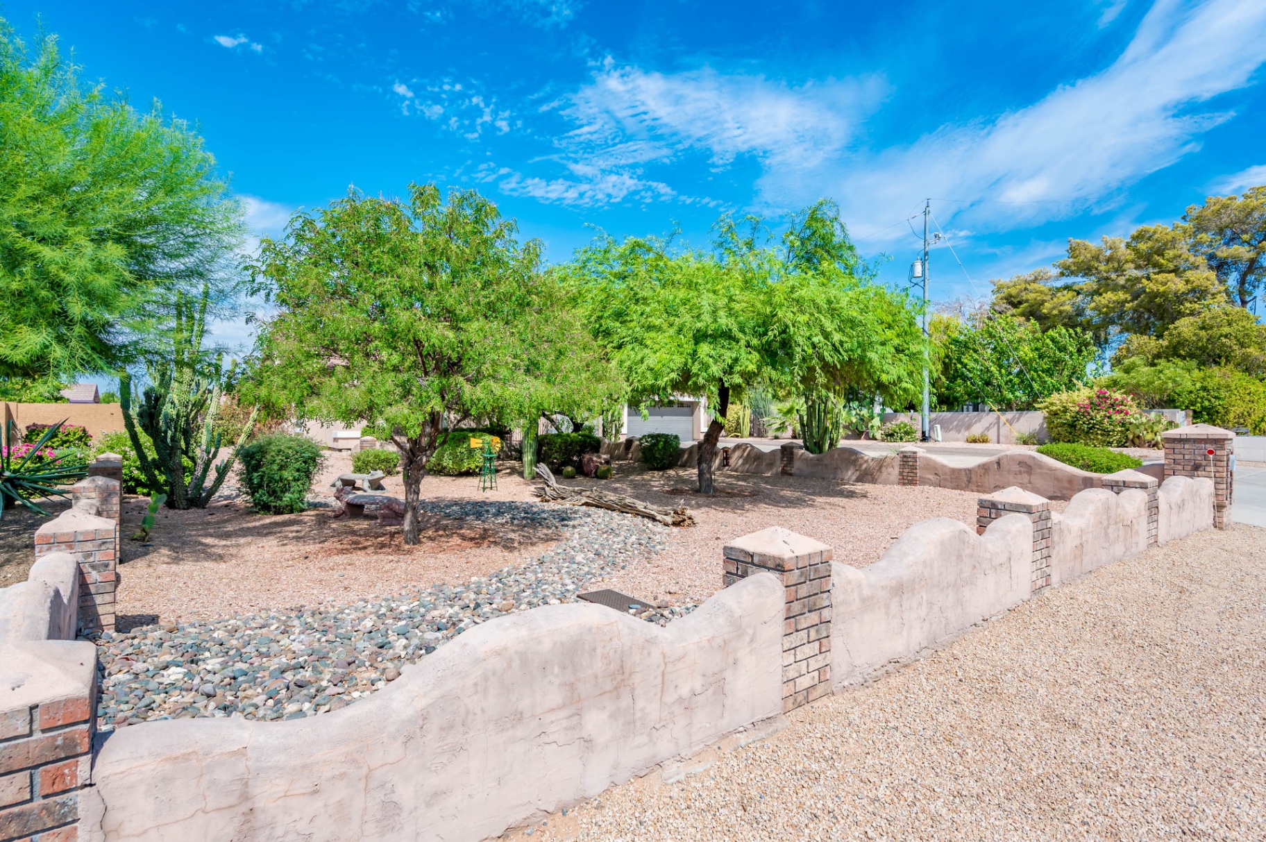 Desert front yard with cacti, brick wall and dry riverbed