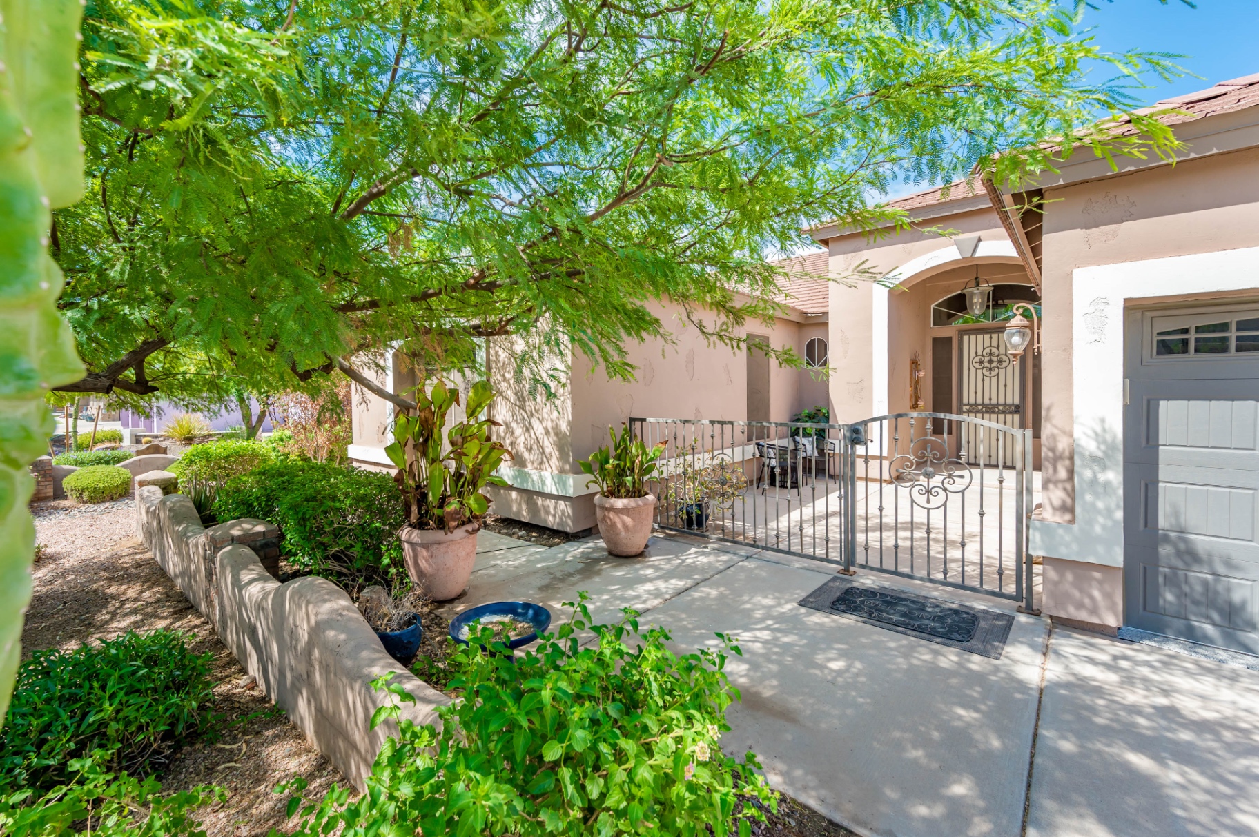 Gated front courtyard with arched entry and lush plants