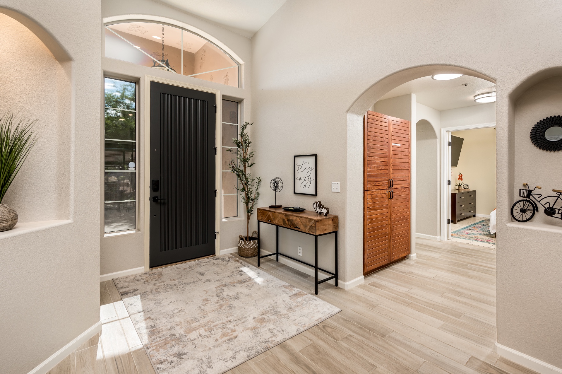 Bright foyer with vaulted ceiling, arched doorways and modern black entry door