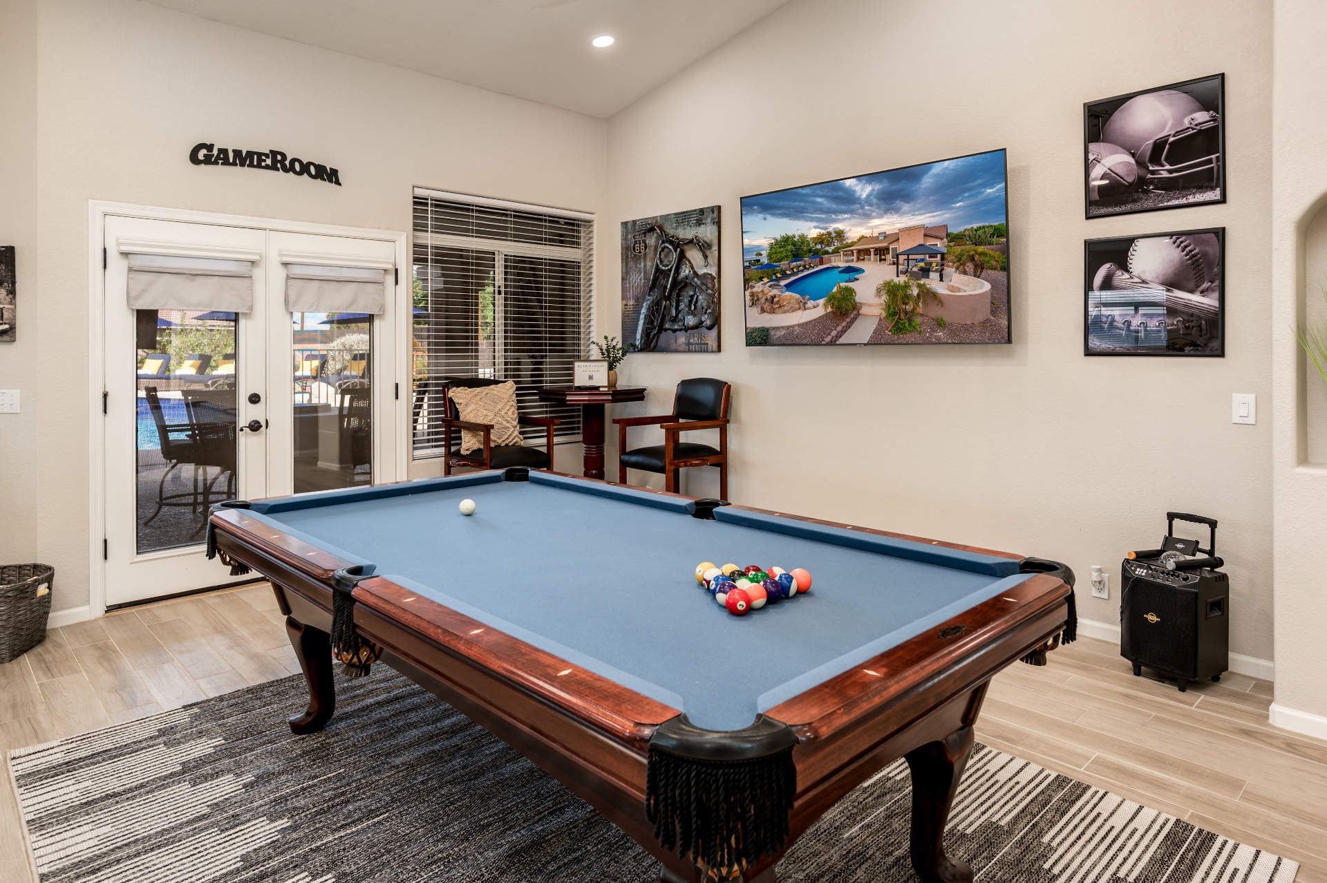 Game room with blue-felt pool table, mounted TV and patio access