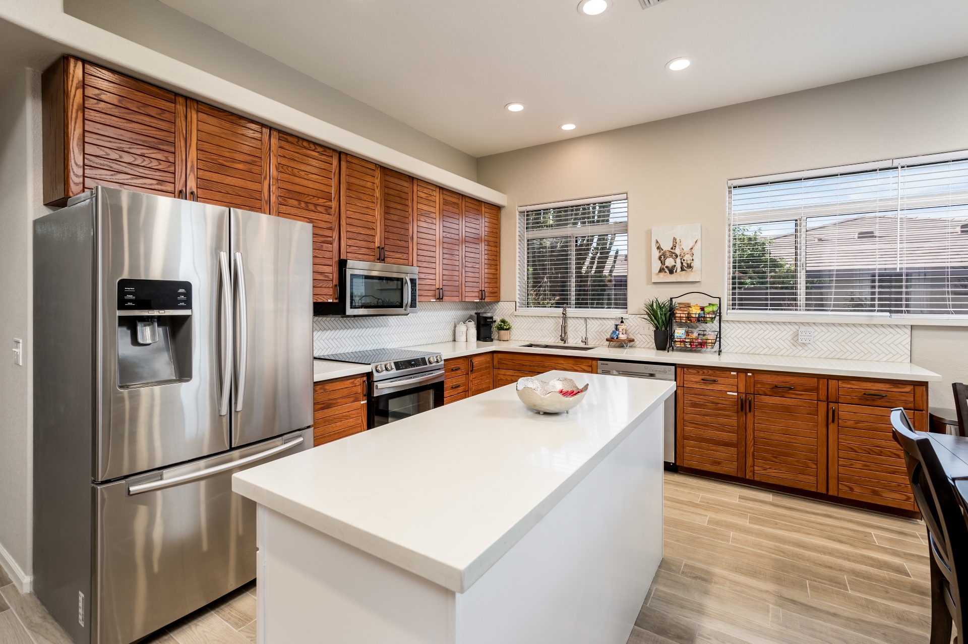 Kitchen with white quartz island, stainless fridge and herringbone backsplash